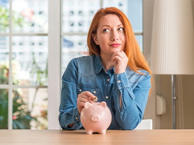 Woman putting a coin into a piggy bank