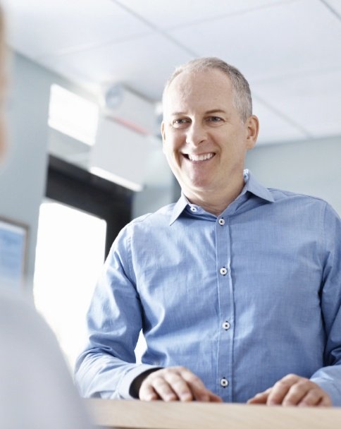 Older man talking to dental team member at front desk