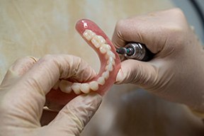 Lab technician filing dentures