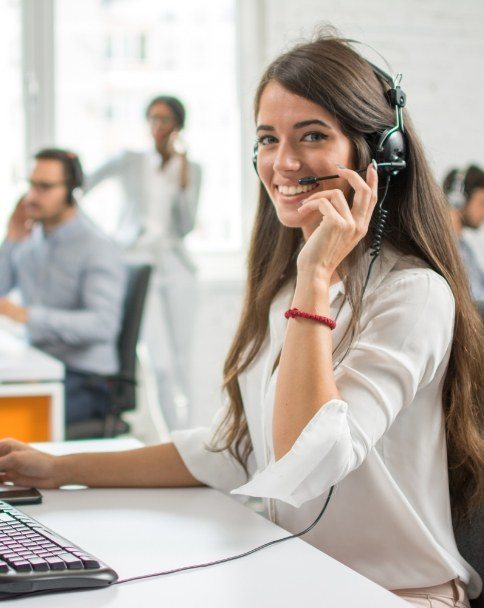 Smiling woman wearing headset and sitting at computer