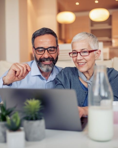 Senior man and woman looking at laptop for dentist reviews in Mesquite